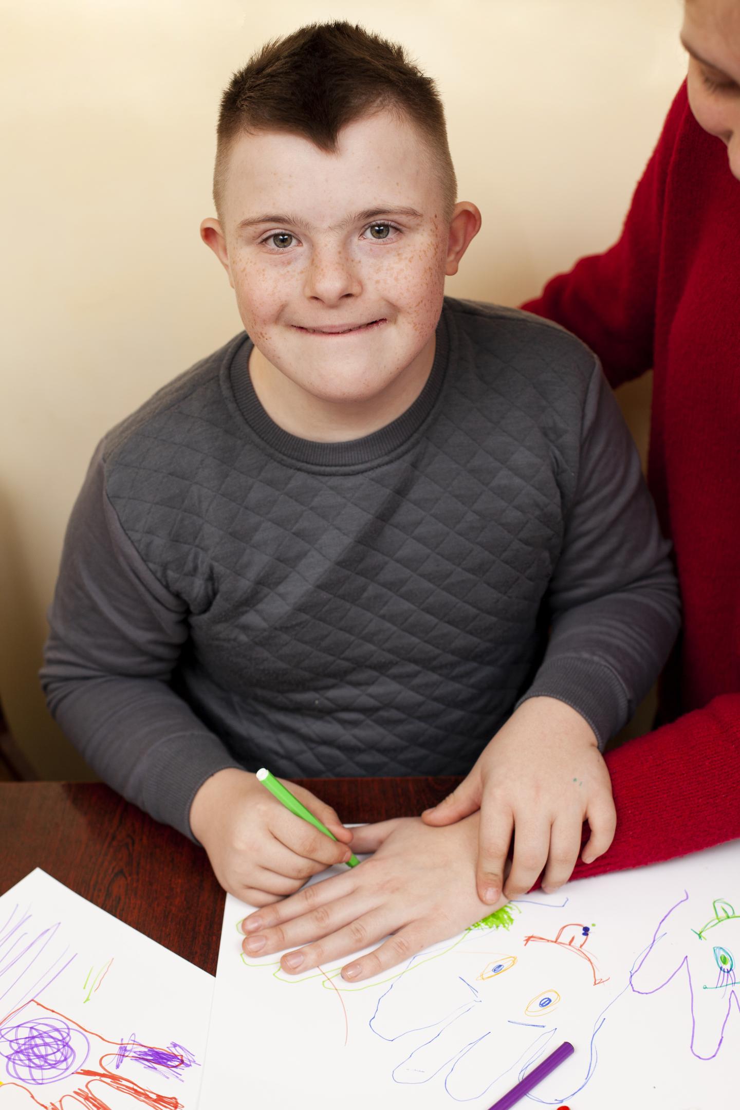 Child with intellectual disability drawing happily